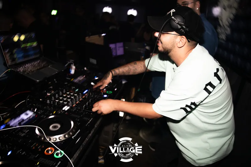 DJ mit schwarzer Kappe und Kopfhörern legt am Pioneer-Pult im Club Village auf